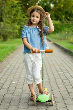 Çocuklu küçük Avrupalı bir kızın portresi bir scooter. Açık havada aktif eğlence.