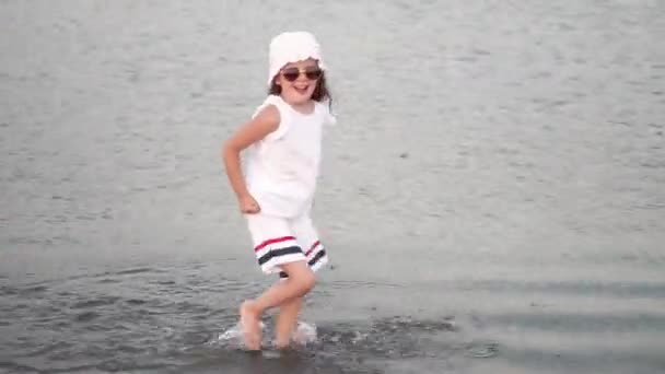 Κομψό Μικρό Ευρωπαϊκό Κορίτσι Ένα Λευκό Κοστούμι Τρέχει Στο Νερό — Αρχείο Βίντεο