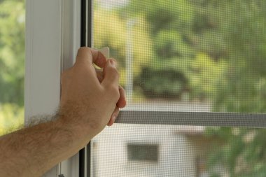 Böceklerden korunma. İnsanın eli geri çekilebilir pil ekran tutucusu pencereyi açmak ya da kapatmak için seçici olarak ele odaklanır