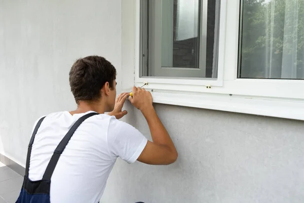 Handyman installing mosquito net, mosquito wire screen on the balcony