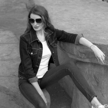 Taş bir bankta oturan bir kız modelin stili. Siyah-beyaz bir fotoğraf..