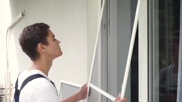 Worker installs new mosquito nets. Workman is installing insect mesh screen on window to protect room from mosquito, fly, insects — Stock Footage Worker Installs New Mosquito Nets Workman Installing Insect Mesh Screen Video Clip