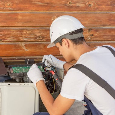 Bir elektrikçi ve klima tamircisi çevirici klimanın çalışmasını kontrol eder