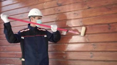 İşçi azı dişi ahşap duvarı boyamaya hazır. Ahşap bir evin bakım ve bakımı kavramı