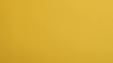 Çikolatalı mısır gevreği topları sarı arka planda bir aşağı bir yukarı hareket ediyor. Yavaş çekim