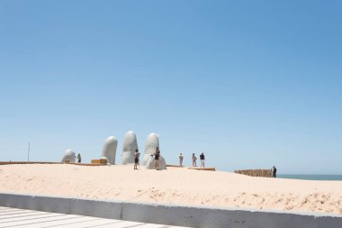 Punta del Este, Maldonado / Uruguay; Jan 1, 2019: The Hand, Fingers or Man Emerging to Life, a popular sculpture of five fingers emerging from the sand clipart