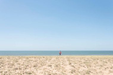 Yazın Uruguay sahilinde ıssız bir sahil. Arkadan denize giderken görülen genç bir adam.
