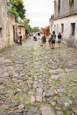 Colonia del Sacramento / Uruguay; 2 Ocak 2019: bulutlu bir yaz sabahı, şehrin tarihi merkezinde, kaldırım taşı sokakta yürüyen turistler