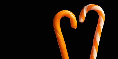 Bir çift cadılar bayramı portakalı ve çizgili baston şeker. Siyah arka planda fotokopi alanı var.