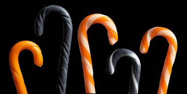 Cadılar Bayramı şeker kamışları seti, siyah arkaplanda turuncu, siyah ve çizgili olanlar.