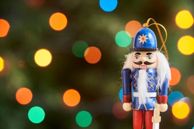 Geleneksel renkli ahşap Noel fındıkkıranı, yeşil arka plan, odak dışı renkli ışıklar, boşluğu kopyala