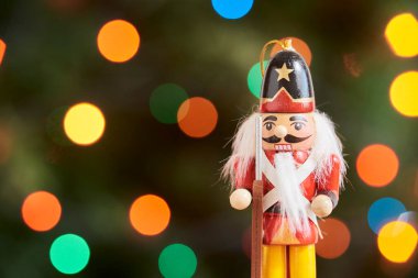 Geleneksel renkli ahşap Noel fındıkkıranı, yeşil arka plan, odak dışı renkli ışıklar, boşluğu kopyala