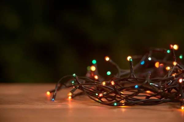 Christmas scene: lighted light cord with different colored lights shining on a wooden surface