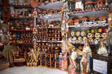 28 Kasım 2022, Paramo, Santander, Kolombiya turistler için bir hediyelik eşya dükkanında raflar dolusu. Dini imgelerin yanındaki posterin metni: Mucizevi kutsal yağ.