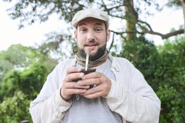 İspanyol adam dışarıda vakit geçirir, içki eşinin tadını çıkarır, geleneksel bir Arjantin aşısı. El Palmar Ulusal Parkı, Entre Rios, Arjantin.