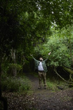 Doğayla iç içe yürüyen bir adam kollarını kaldırırken yukarı bakmak için yolun ortasında durur. El Palmar Ulusal Parkı, Arjantin. Kavramlar: eko-turizm, doğayla bağlantı kurmak için seyahat