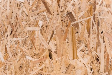 OSB tahtaları ahşap bir zemine zımparalanmış kahverengi odun parçalarından yapılmıştır. OSB ahşap kaplama arka planının üst görüntüsü, sıkı, pürüzsüz yüzey. Oryantasyon Strand Kurulu. Süpürge tahtası. Sterling tahtası. Aspenite