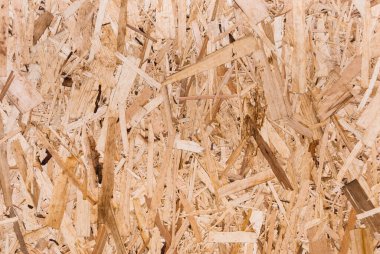 OSB tahtaları ahşap bir zemine zımparalanmış kahverengi odun parçalarından yapılmıştır. OSB ahşap kaplama arka planının üst görüntüsü, sıkı, pürüzsüz yüzey. Oryantasyon Strand Kurulu. Süpürge tahtası. Sterling tahtası. Aspenite