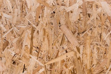 OSB tahtaları ahşap bir zemine zımparalanmış kahverengi odun parçalarından yapılmıştır. OSB ahşap kaplama arka planının üst görüntüsü, sıkı, pürüzsüz yüzey. Oryantasyon Strand Kurulu. Süpürge tahtası. Sterling tahtası. Aspenite