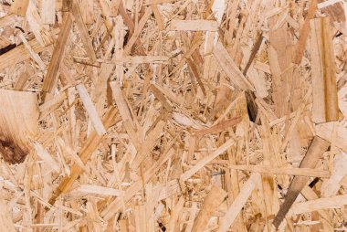 OSB tahtaları ahşap bir zemine zımparalanmış kahverengi odun parçalarından yapılmıştır. OSB ahşap kaplama arka planının üst görüntüsü, sıkı, pürüzsüz yüzey. Oryantasyon Strand Kurulu. Süpürge tahtası. Sterling tahtası. Aspenite