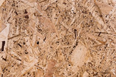 OSB tahtaları ahşap bir zemine zımparalanmış kahverengi odun parçalarından yapılmıştır. OSB ahşap kaplama arka planının üst görüntüsü, sıkı, pürüzsüz yüzey. Oryantasyon Strand Kurulu. Süpürge tahtası. Sterling tahtası. Aspenite