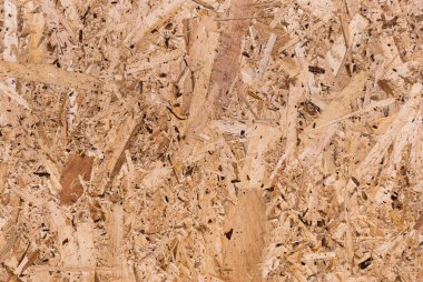 OSB tahtaları ahşap bir zemine zımparalanmış kahverengi odun parçalarından yapılmıştır. OSB ahşap kaplama arka planının üst görüntüsü, sıkı, pürüzsüz yüzey. Oryantasyon Strand Kurulu. Süpürge tahtası. Sterling tahtası. Aspenite