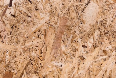 OSB tahtaları ahşap bir zemine zımparalanmış kahverengi odun parçalarından yapılmıştır. OSB ahşap kaplama arka planının üst görüntüsü, sıkı, pürüzsüz yüzey. Oryantasyon Strand Kurulu. Süpürge tahtası. Sterling tahtası. Aspenite