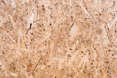 OSB tahtaları ahşap bir zemine zımparalanmış kahverengi odun parçalarından yapılmıştır. OSB ahşap kaplama arka planının üst görüntüsü, sıkı, pürüzsüz yüzey. Oryantasyon Strand Kurulu. Süpürge tahtası. Sterling tahtası. Aspenite