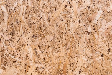OSB tahtaları ahşap bir zemine zımparalanmış kahverengi odun parçalarından yapılmıştır. OSB ahşap kaplama arka planının üst görüntüsü, sıkı, pürüzsüz yüzey. Oryantasyon Strand Kurulu. Süpürge tahtası. Sterling tahtası. Aspenite