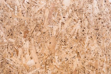 OSB tahtaları ahşap bir zemine zımparalanmış kahverengi odun parçalarından yapılmıştır. OSB ahşap kaplama arka planının üst görüntüsü, sıkı, pürüzsüz yüzey. Oryantasyon Strand Kurulu. Süpürge tahtası. Sterling tahtası. Aspenite