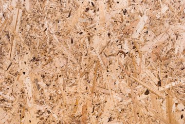OSB tahtaları ahşap bir zemine zımparalanmış kahverengi odun parçalarından yapılmıştır. OSB ahşap kaplama arka planının üst görüntüsü, sıkı, pürüzsüz yüzey. Oryantasyon Strand Kurulu. Süpürge tahtası. Sterling tahtası. Aspenite