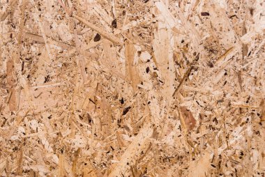OSB tahtaları ahşap bir zemine zımparalanmış kahverengi odun parçalarından yapılmıştır. OSB ahşap kaplama arka planının üst görüntüsü, sıkı, pürüzsüz yüzey. Oryantasyon Strand Kurulu. Süpürge tahtası. Sterling tahtası. Aspenite