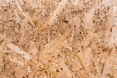 OSB tahtaları ahşap bir zemine zımparalanmış kahverengi odun parçalarından yapılmıştır. OSB ahşap kaplama arka planının üst görüntüsü, sıkı, pürüzsüz yüzey. Oryantasyon Strand Kurulu. Süpürge tahtası. Sterling tahtası. Aspenite
