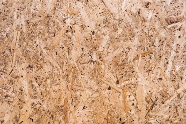 OSB tahtaları ahşap bir zemine zımparalanmış kahverengi odun parçalarından yapılmıştır. OSB ahşap kaplama arka planının üst görüntüsü, sıkı, pürüzsüz yüzey. Oryantasyon Strand Kurulu. Süpürge tahtası. Sterling tahtası. Aspenite