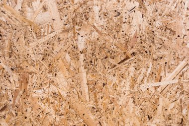 OSB tahtaları ahşap bir zemine zımparalanmış kahverengi odun parçalarından yapılmıştır. OSB ahşap kaplama arka planının üst görüntüsü, sıkı, pürüzsüz yüzey. Oryantasyon Strand Kurulu. Süpürge tahtası. Sterling tahtası. Aspenite