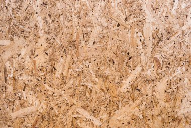 OSB tahtaları ahşap bir zemine zımparalanmış kahverengi odun parçalarından yapılmıştır. OSB ahşap kaplama arka planının üst görüntüsü, sıkı, pürüzsüz yüzey. Oryantasyon Strand Kurulu. Süpürge tahtası. Sterling tahtası. Aspenite