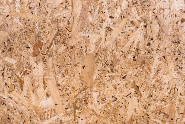 OSB tahtaları ahşap bir zemine zımparalanmış kahverengi odun parçalarından yapılmıştır. OSB ahşap kaplama arka planının üst görüntüsü, sıkı, pürüzsüz yüzey. Oryantasyon Strand Kurulu. Süpürge tahtası. Sterling tahtası. Aspenite