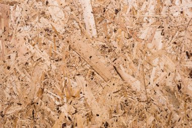 OSB tahtaları ahşap bir zemine zımparalanmış kahverengi odun parçalarından yapılmıştır. OSB ahşap kaplama arka planının üst görüntüsü, sıkı, pürüzsüz yüzey. Oryantasyon Strand Kurulu. Süpürge tahtası. Sterling tahtası. Aspenite