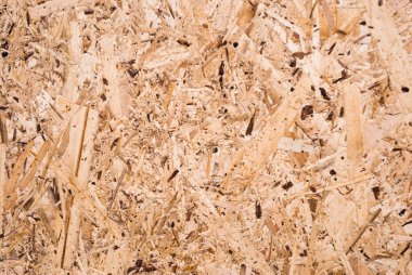 OSB tahtaları ahşap bir zemine zımparalanmış kahverengi odun parçalarından yapılmıştır. OSB ahşap kaplama arka planının üst görüntüsü, sıkı, pürüzsüz yüzey. Oryantasyon Strand Kurulu. Süpürge tahtası. Sterling tahtası. Aspenite