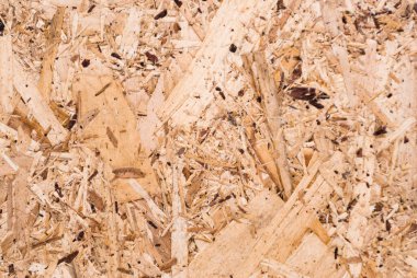 OSB tahtaları ahşap bir zemine zımparalanmış kahverengi odun parçalarından yapılmıştır. OSB ahşap kaplama arka planının üst görüntüsü, sıkı, pürüzsüz yüzey. Oryantasyon Strand Kurulu. Süpürge tahtası. Sterling tahtası. Aspenite