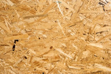 OSB tahtaları ahşap bir zemine zımparalanmış kahverengi odun parçalarından yapılmıştır. OSB ahşap kaplama arka planının üst görüntüsü, sıkı, pürüzsüz yüzey. Oryantasyon Strand Kurulu. Süpürge tahtası. Sterling tahtası. Aspenite