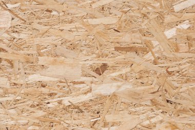 OSB tahtaları ahşap bir zemine zımparalanmış kahverengi odun parçalarından yapılmıştır. OSB ahşap kaplama arka planının üst görüntüsü, sıkı, pürüzsüz yüzey. Oryantasyon Strand Kurulu. Süpürge tahtası. Sterling tahtası. Aspenite