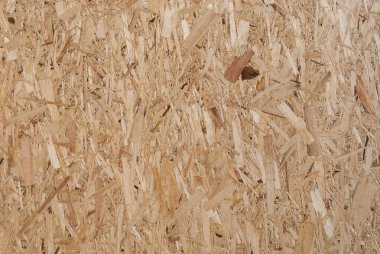 OSB tahtaları ahşap bir zemine zımparalanmış kahverengi odun parçalarından yapılmıştır. OSB ahşap kaplama arka planının üst görüntüsü, sıkı, pürüzsüz yüzey. Oryantasyon Strand Kurulu. Süpürge tahtası. Sterling tahtası. Aspenite