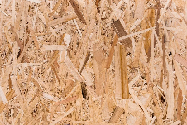 OSB tahtaları ahşap bir zemine zımparalanmış kahverengi odun parçalarından yapılmıştır. OSB ahşap kaplama arka planının üst görüntüsü, sıkı, pürüzsüz yüzey. Oryantasyon Strand Kurulu. Süpürge tahtası. Sterling tahtası. Aspenite