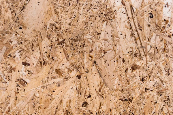 OSB boards are made of brown wood chips sanded into a wooden background. Top view of OSB wood veneer background, tight, seamless surface. Oriented Strand Board. Flake board. Sterling board. Aspenite