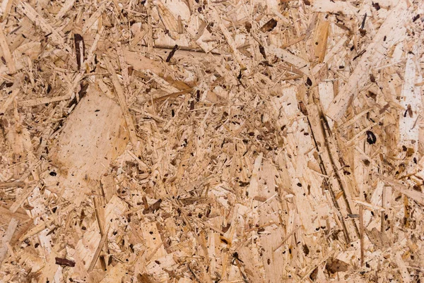 OSB boards are made of brown wood chips sanded into a wooden background. Top view of OSB wood veneer background, tight, seamless surface. Oriented Strand Board. Flake board. Sterling board. Aspenite