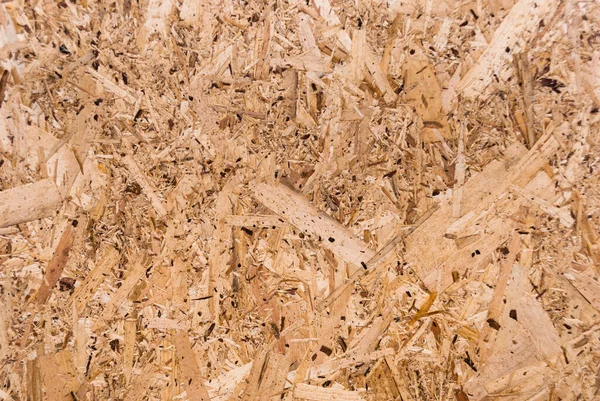 OSB tahtaları ahşap bir zemine zımparalanmış kahverengi odun parçalarından yapılmıştır. OSB ahşap kaplama arka planının üst görüntüsü, sıkı, pürüzsüz yüzey. Oryantasyon Strand Kurulu. Süpürge tahtası. Sterling tahtası. Aspenite