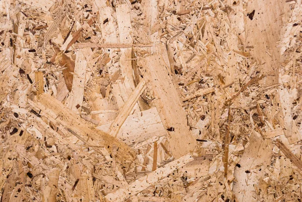 OSB boards are made of brown wood chips sanded into a wooden background. Top view of OSB wood veneer background, tight, seamless surface. Oriented Strand Board. Flake board. Sterling board. Aspenite