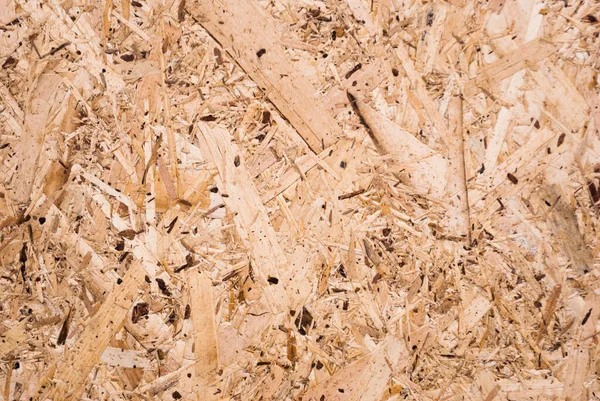 OSB boards are made of brown wood chips sanded into a wooden background. Top view of OSB wood veneer background, tight, seamless surface. Oriented Strand Board. Flake board. Sterling board. Aspenite