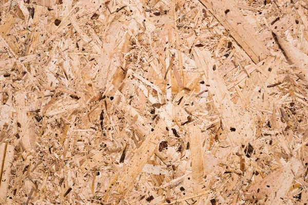 OSB boards are made of brown wood chips sanded into a wooden background. Top view of OSB wood veneer background, tight, seamless surface. Oriented Strand Board. Flake board. Sterling board. Aspenite